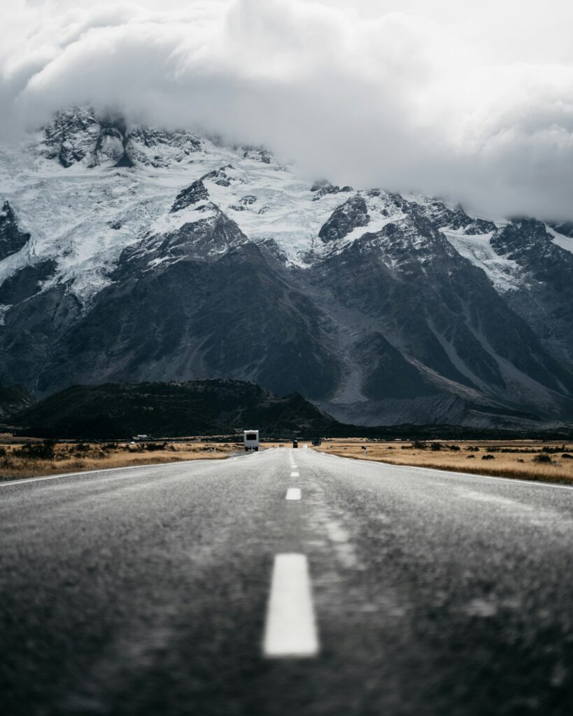 Vertical shot of a road on the background of the snowy rock in Mount Cook National Park